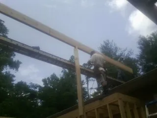 Carpenter setting a ridge beam over a new addition frame — Ice Dam Removal by Roofing Brothers in Bellport