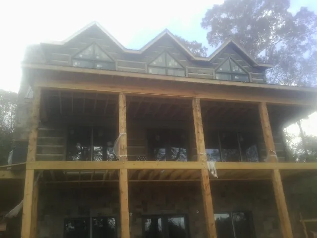 Dormers and porch framing on a large log home under construction — Roof Coating work by our crew in Bellport
