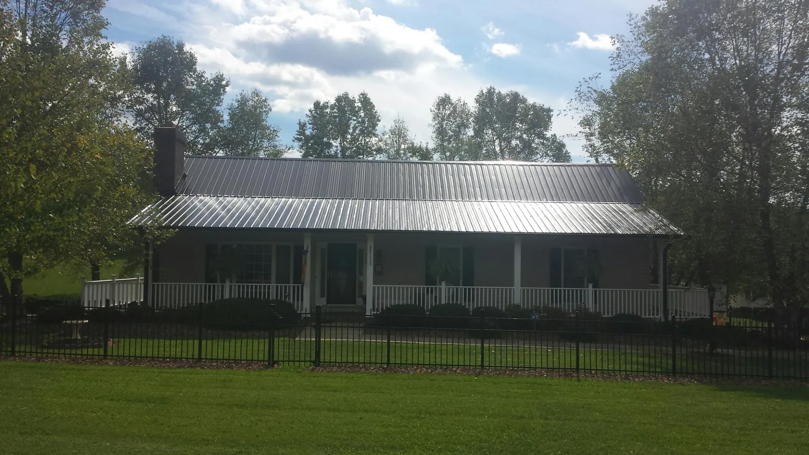 Gray metal roof on a brick ranch with a full width front porch — Gutter Guard Installation work by our crew in Bellport