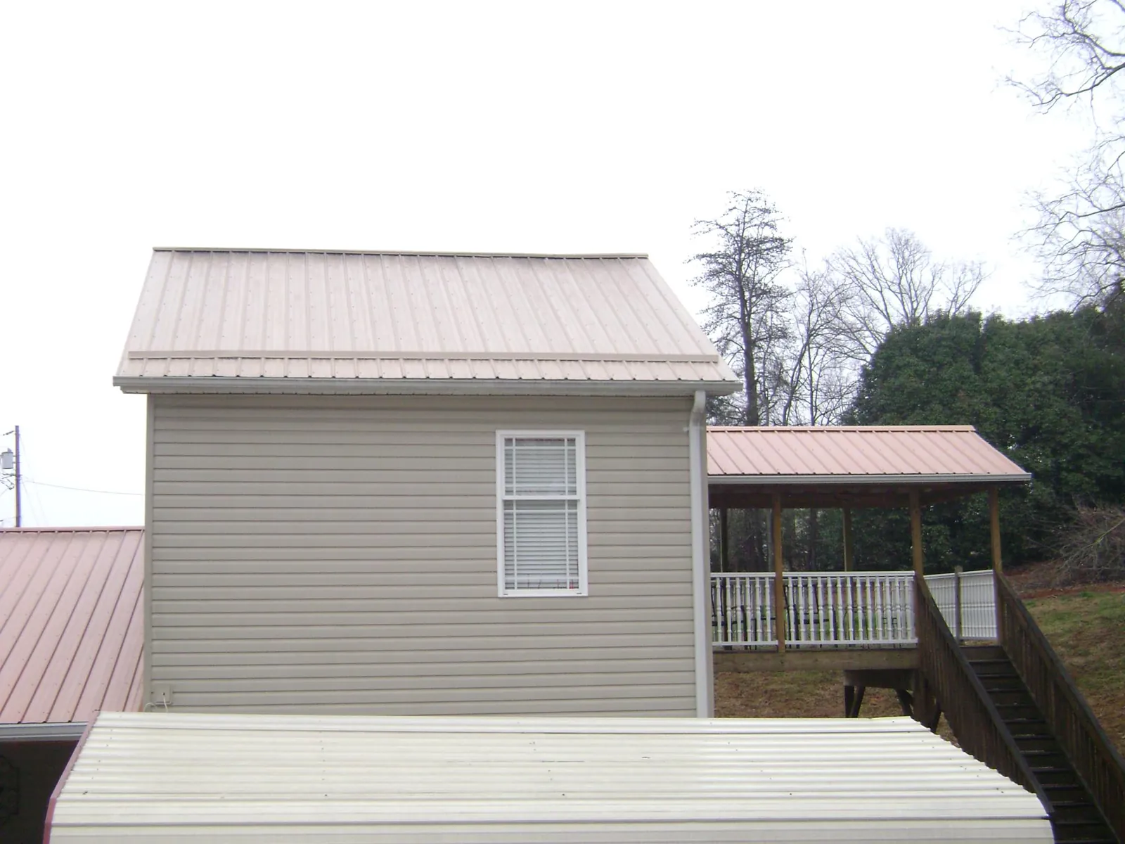 Tan metal roofs on a two story addition and attached porch in Bellport