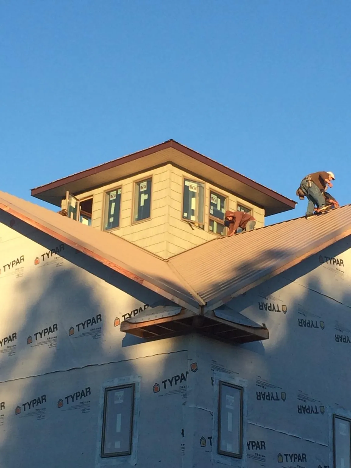 Roofers working around a rooftop cupola on a new metal roof at sunset — Roof Waterproofing in Bellport by Roofing Brothers
